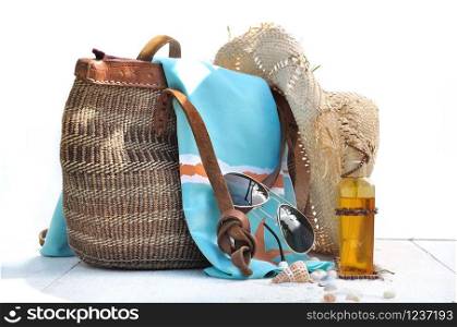 beach bag and accessories on white wooden plank with shells
