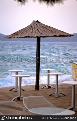 Beach bar parasol by rough sea vertical view, Zadar, Croatia