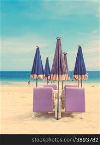 Beach chair and umbrella on tropical sand beach with retro filter effect