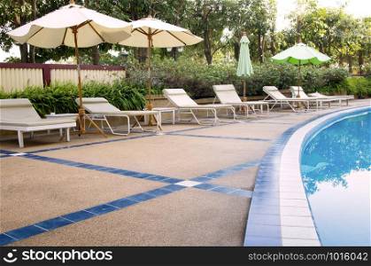 Beach chairs and umbrella on swimming pool