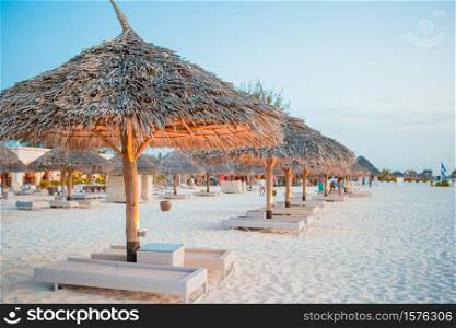 Beach chairs on exotic tropical white sandy beach. Beach wooden chairs and umbrellas for vacations on beach in Greece