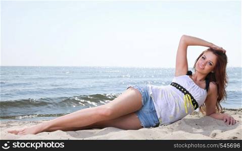 Beach holidays woman enjoying summer sun lie in sand looking happy at copy space. Beautiful young model
