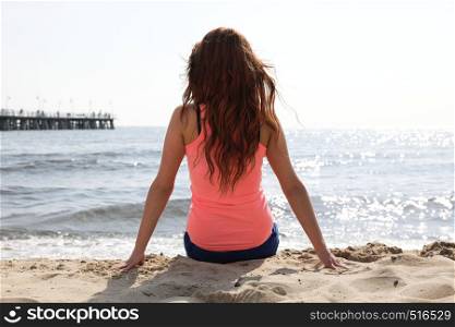 Beach holidays woman enjoying summer sun sitting in sand looking happy at copy space. Beautiful young model