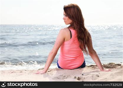 Beach holidays woman enjoying summer sun sitting in sand looking happy at copy space. Beautiful young model