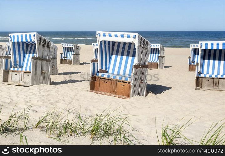 Beach landscape with empty wicker chairs, fine sand, and blue water sea, on sunny day. Beach resort in North Germany at the Wadden sea on Sylt island.