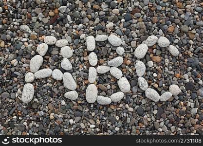 Beach, letters A, B, C combined from white stones, on dark pebble.