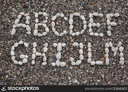 Beach, letters of alphabet made of white stones on dark pebbles. First half