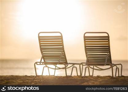 Beach lounge chairs on beautiful tropical beach at sunset. White lounge chairs on a beautiful tropical beach at Maldives
