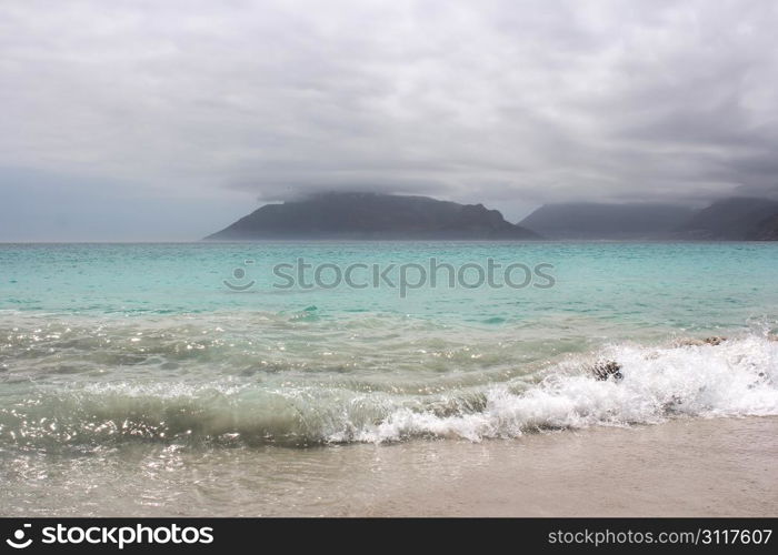 Beach of Kommetjie with an upcoming storm in the background and blue water