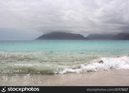 Beach of Kommetjie with an upcoming storm in the background and blue water