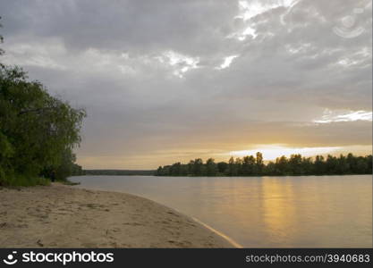 beach on the river at sunset with trees