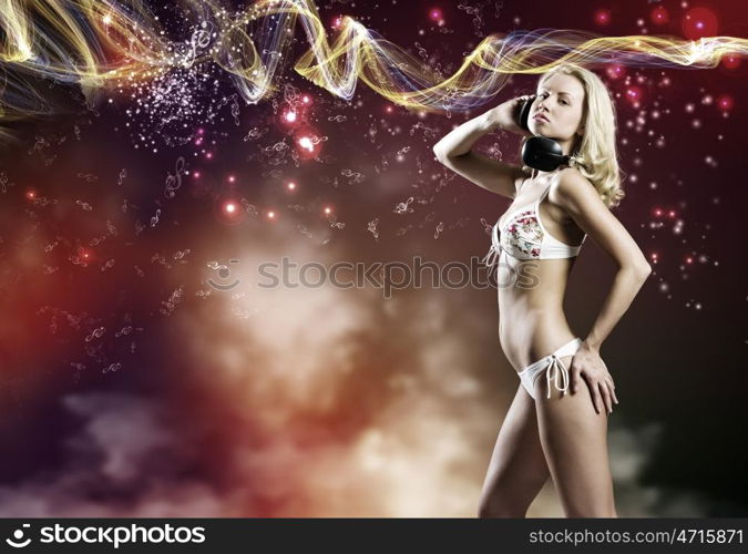 Beach party. Young pretty blonde in bikini dancing with headphones on head