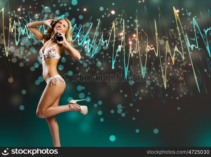 Beach party. Young pretty blonde in bikini dancing with headphones on head