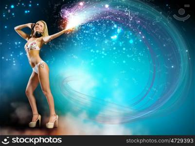 Beach party. Young pretty blonde in bikini dancing with headphones on head