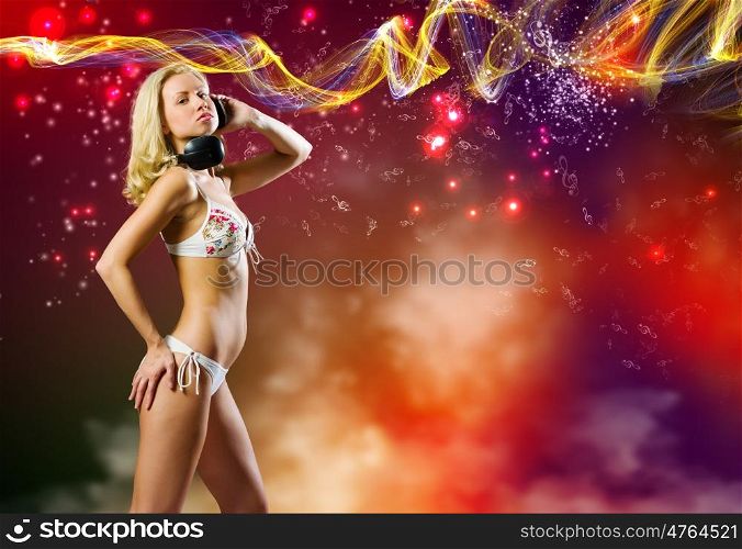 Beach party. Young pretty blonde in bikini dancing with headphones on head