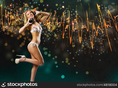 Beach party. Young pretty blonde in bikini dancing with headphones on head