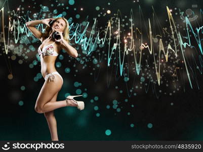 Beach party. Young pretty woman in white bikini wearing headphones