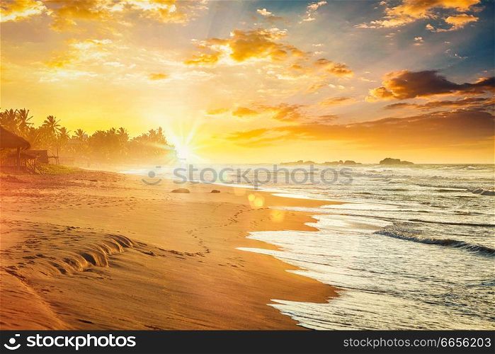 Beach resort vacation holidays background - tropical sunset on ocean beach. Sri Lanka. With light leak and lens flare. Ocean sunset , Sri Lanka