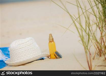 Beach set summer hat sunglasses and skin lotion lying on the sand. Vacation resting and relax