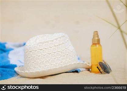 Beach set summer hat sunglasses and skin lotion lying on the sand. Vacation resting and relax