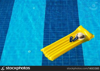 Beach summer holiday background. Inflatable air mattress, flip flops and hat on swimming pool.