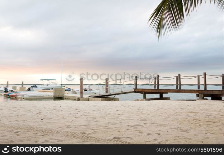 beach, summer, travel and leisure concept - boats moored to pier