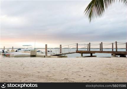beach, summer, travel and leisure concept - boats moored to pier