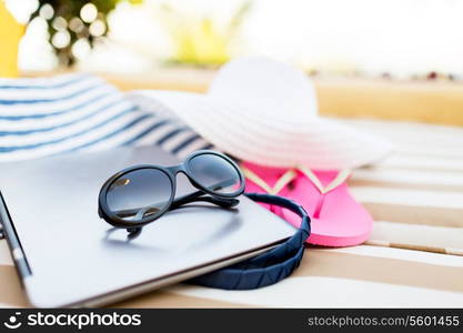 beach, summer, vacation, accessories and technology concept - close up of laptop and summer accessories on beach