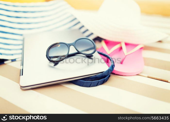 beach, summer, vacation, accessories and technology concept - close up of laptop and summer accessories on beach