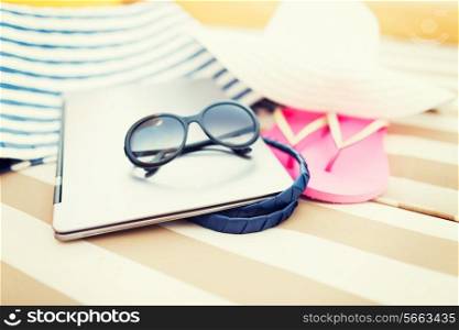 beach, summer, vacation, accessories and technology concept - close up of laptop and summer accessories on beach