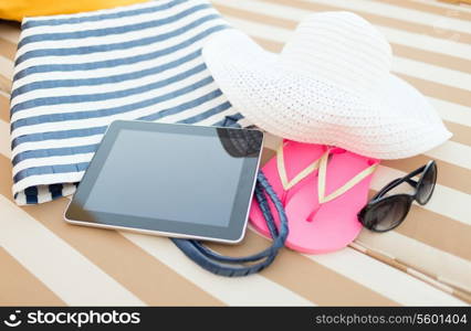 beach, summer, vacation, accessories and technology concept - close up of tablet pc computer and summer accessories on beach