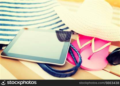 beach, summer, vacation, accessories and technology concept - close up of tablet pc computer and summer accessories on beach