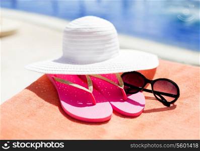 beach, summer, vacation and accessories concept - close up of hat, flip-flops and sunglasses at pool