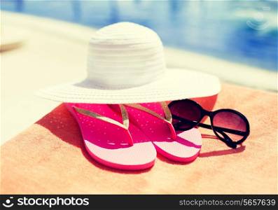 beach, summer, vacation and accessories concept - close up of hat, flip-flops and sunglasses at pool