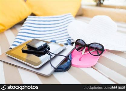 beach, summer vacation and technology concept - close up of tablet pc, notebook, smartphone and summer accessories on beach