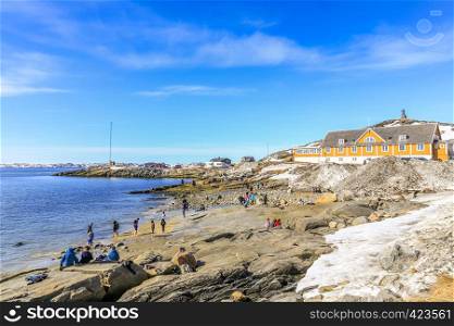 Beach time for Inuit people enjoying the sunny May day at the sea fjord, Nuuk city, Greenland