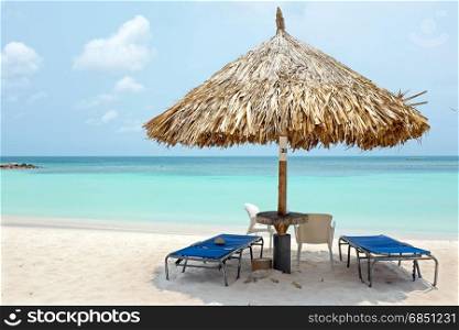 Beach umbrella and beach chairs on Palm Beach at Aruba island in the Caribbean Sea