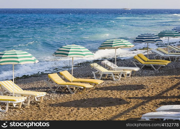 Beach umbrellas and lounge chairs on the beach, Rhodes, Dodecanese Islands, Greece