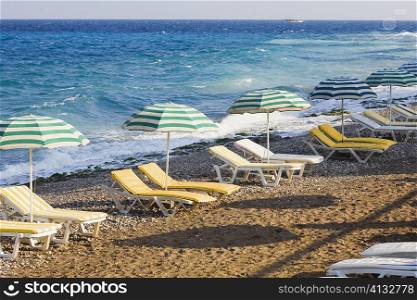 Beach umbrellas and lounge chairs on the beach, Rhodes, Dodecanese Islands, Greece