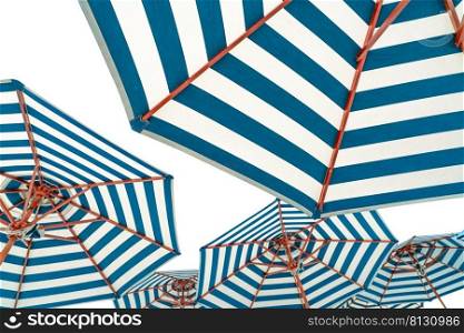 Beach umbrellas isolated on white background. Blue and white striped beach parasol for summer vacation concept. Umbrella for tropical beach in summer. Sunshade for resort decoration. Holiday travel.