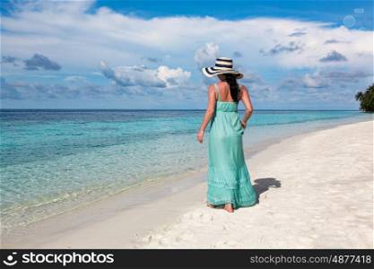 Beach vacation. Girl walking along a tropical beach in the Maldives.