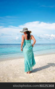 Beach vacation. Girl walking along a tropical beach in the Maldives.