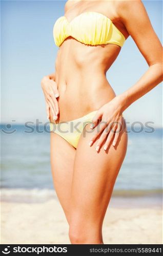 beach, vacation, summer holidays and body concept - closeup of female body in bikini at beach