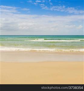 Beach with blue sky and blue water lapping the sand