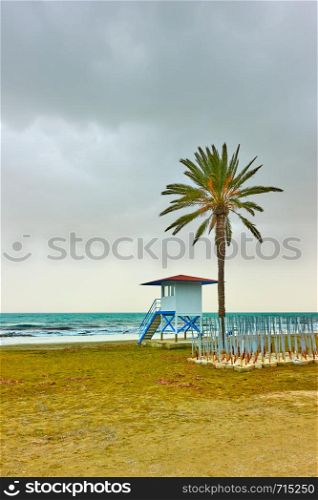Beach with palm tree and life guard tower in low season, Larnaca, Cyprus