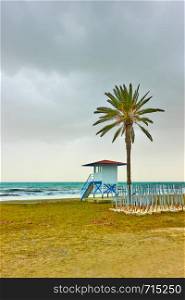 Beach with palm tree and life guard tower in low season, Larnaca, Cyprus