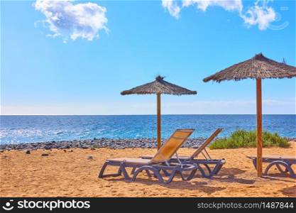 Beach with parasols and chaise longues by the sea at seaside resort on sunny summer day