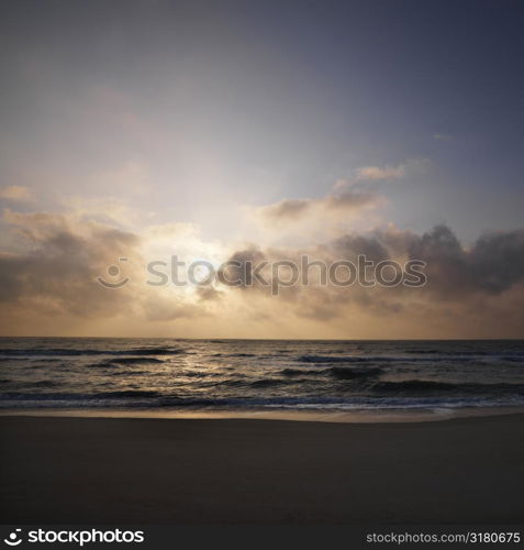 Beach with sun setting in clouds over ocean at Bald Head Island, North Carolina