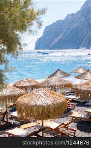 beach with umbrellas and deck chairs in Santorini