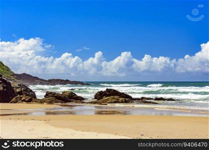 Beach with waves breaking against the rocks on a sunny day in the town of Serra Grande on the coast of Bahia. Beach with waves breaking against the rocks